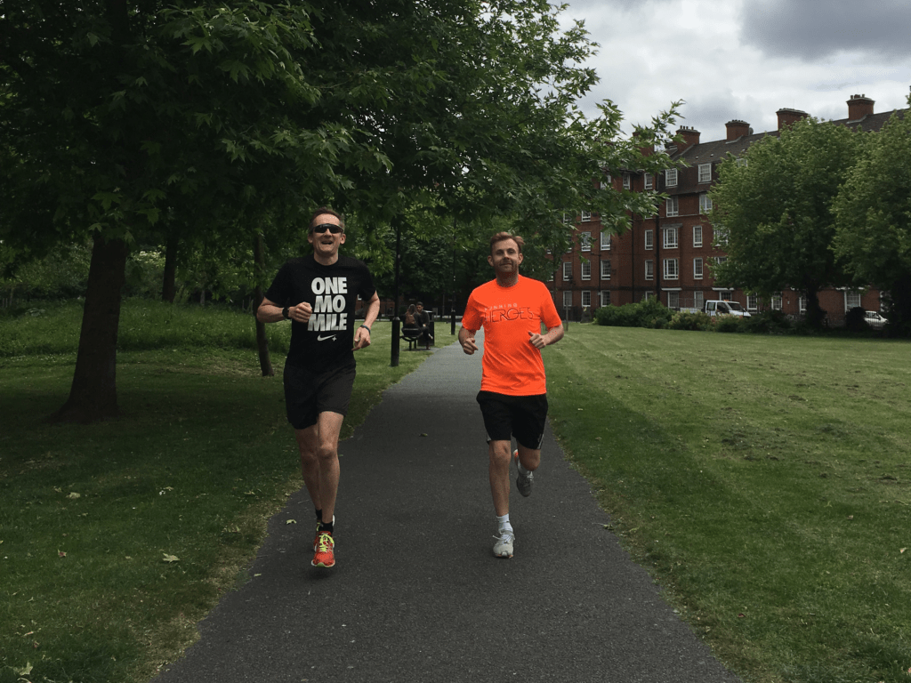 Two men running side by side in a park